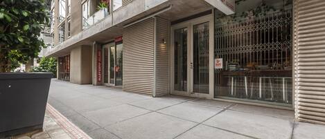Vista de la calle con comercios cerrados, incluyendo una pizzería, y un edificio con entrada visible.
