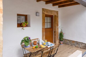 A wooden table set for breakfast with a window, a door, and potted plants.