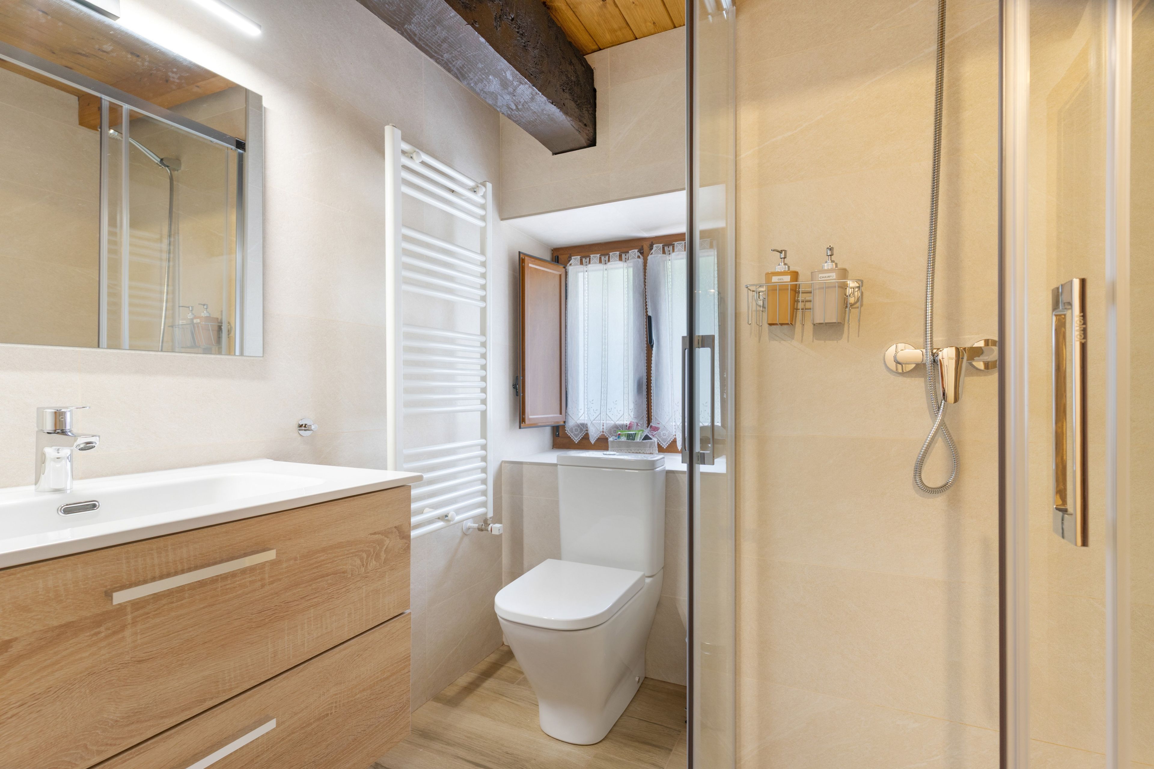Une salle de bain moderne avec un lavabo blanc, un meuble-lavabo en bois, des toilettes et une cabine de douche en verre.