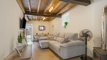 Una sala moderna con un sofá modular, un ventilador de pie y un techo de madera.