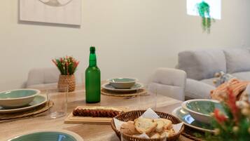 Une table à manger avec des assiettes, des verres, une bouteille et un panier de pain.