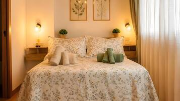 A bedroom with a wooden ceiling, a floral bedspread, two wall-mounted lamps, and a framed botanical print.