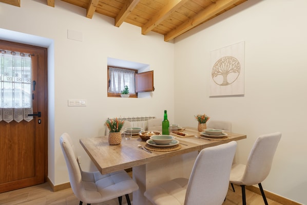 A dining area with a wooden table, chairs, and a window with curtains.