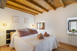 A bedroom with a bed, pillows, a window with a view, and a radiator.