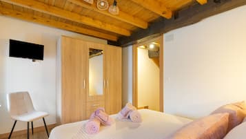 Een slaapkamer met een bed, een stoel, een kledingkast en een televisie aan de muur.
