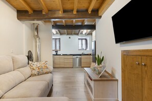 A modern living room with a sofa, a wooden cabinet, and a flat-screen TV mounted on the wall.