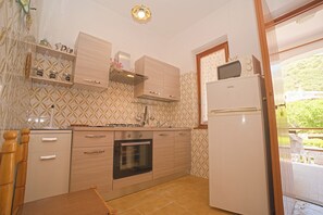 A compact kitchen with a built-in oven, a microwave, and a refrigerator. - Margherita-3 by Appartamenti Margherita seafront accommodation in Giglio Campese (Giglio Campese)