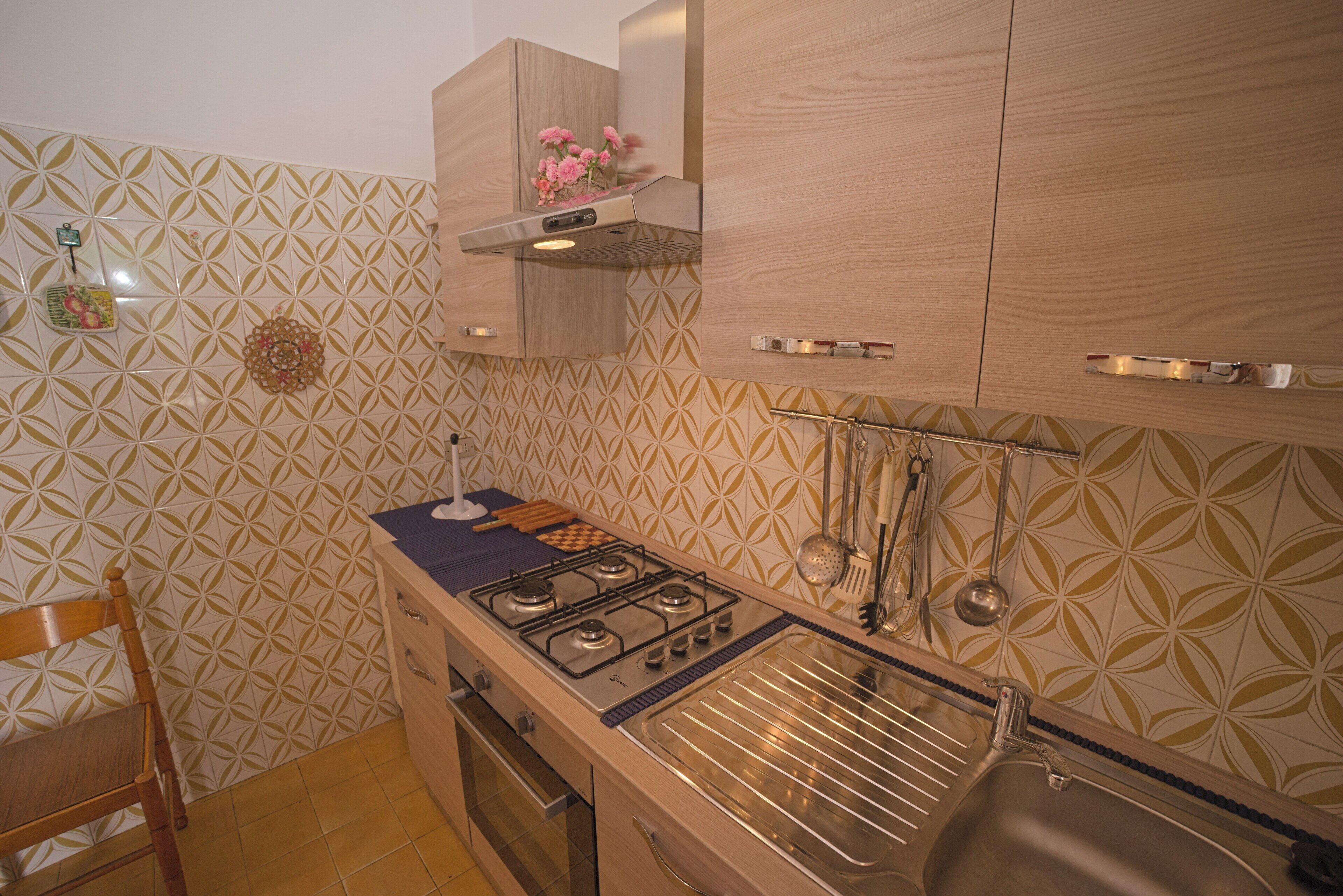 A kitchen with a gas stove, wooden cabinets, and a patterned backsplash.