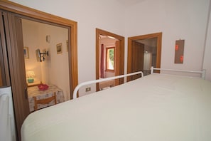 A bedroom with a bed, a bedside table, a chair, and a window. - Margherita-3 by Appartamenti Margherita seafront accommodation in Giglio Campese (Giglio Campese)