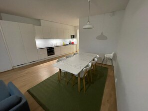 Eine moderne Küche mit weißen Schränken, einem Esstisch mit Stühlen und einem grünen Teppich.