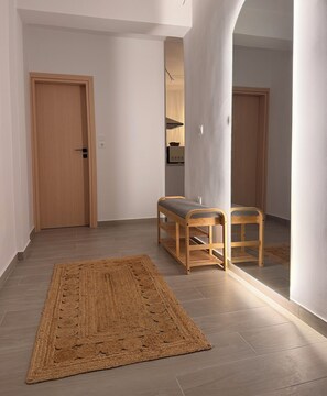 A hallway with a wooden door, a bench, and a woven rug. - Apartment in Thiseio, just a stone's throw from the Acropolis (Athina)
