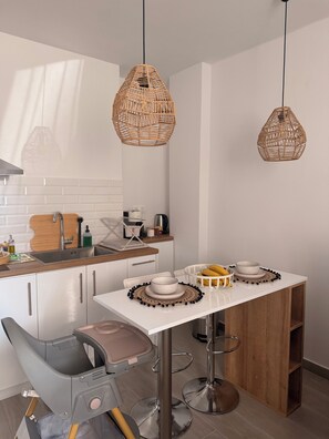A modern kitchen with white cabinets, a wooden countertop, and two hanging wicker pendant lights. - Apartment in Thiseio, just a stone's throw from the Acropolis (Athina)