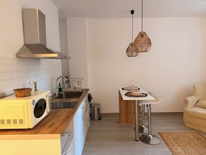 A modern kitchen with a built-in oven, a stainless steel sink, and a hanging light fixture. - Apartment in Thiseio, just a stone's throw from the Acropolis (Athina)