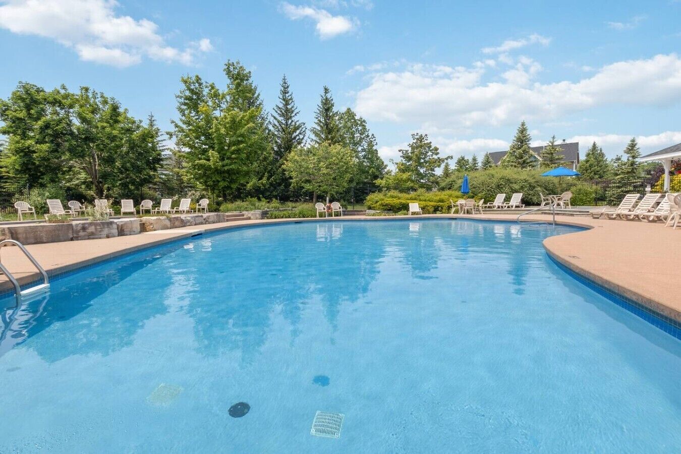 En swimmingpool med liggestole og en klar himmel.