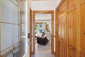 A hallway with wooden doors, a seating area with a massage chair, and a view of the outdoors.