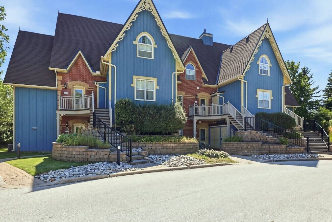 A multi-story house with a prominent front porch, a staircase leading to the second floor, and a well-maintained front yard.