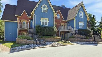A multi-story house with a prominent front porch, a staircase leading to the second floor, and a well-maintained front yard.