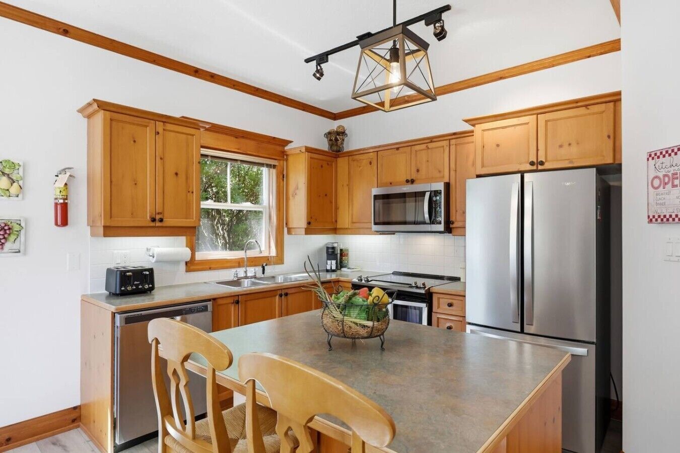 Una cocina moderna con armarios de madera, electrodomésticos de acero inoxidable y una isla central con sillas.