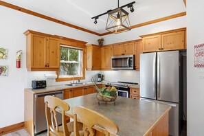 A modern kitchen with wooden cabinets, stainless steel appliances, and a central island with chairs.