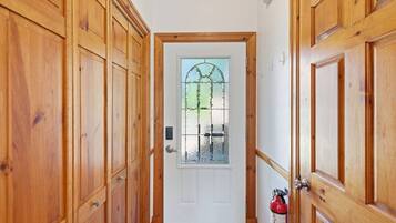 A wooden door with a glass window, a fire extinguisher, and a doormat.