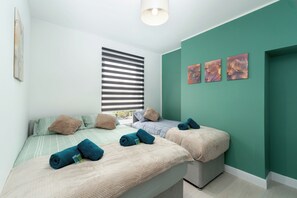 Un dormitorio con dos camas, un ventanal con persianas y tres cuadros colgados en la pared.