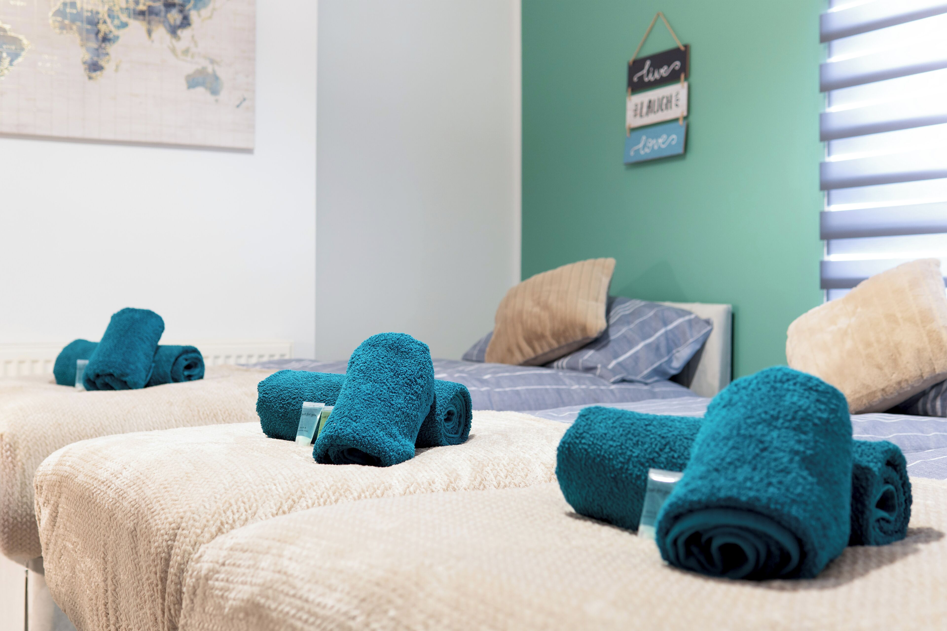 A hotel room with two beds, each with a rolled towel and a pillow.