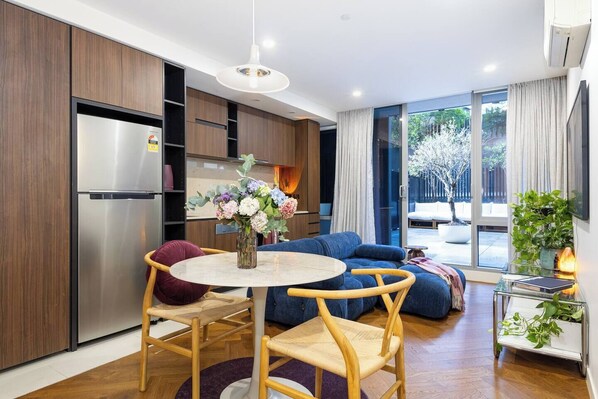 Un espacio habitable moderno con comedor, cocina y ventanas amplias.