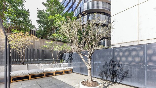 Un espace extérieur aménagé avec un canapé et un bac à fleurs contenant un arbre.