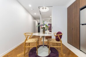 Un comedor moderno con una mesa redonda, dos sillas, un jarrón de flores y una lámpara colgante.