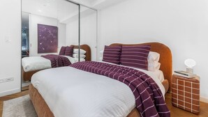 Quarto moderno com uma cama grande, um espelho e uma mesinha de cabeceira.