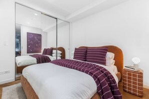 Un dormitorio moderno con una cama grande, un espejo y una mesita de noche.