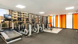 Une salle de sport équipée de tapis de course, de vélos elliptiques et d'appareils de musculation.