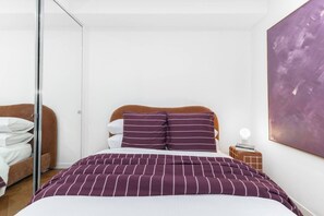 Ein Schlafzimmer mit einem Bett, einem Nachttisch, einer Wanddekoration und einer Ablage.