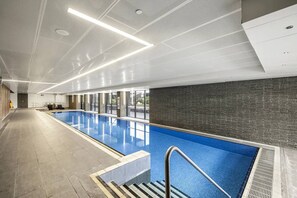 Ein langer, überdachter Schwimmteich mit Fliesenboden, einer Metallhandstange und einer Decke mit Einbaustrahlern.