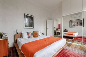 Moderni hotellihuone, jossa on suuri sänky, työpöytä ja peili.