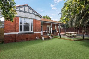 A residential property with a brick exterior, a covered patio, and a well-maintained lawn.