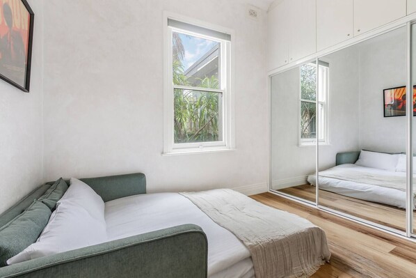 A bedroom with a bed, a large mirror, and a window.