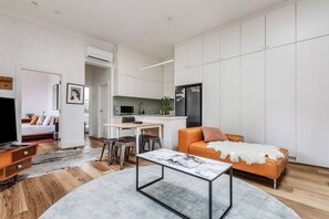A modern apartment with a living room, dining area, kitchen, and a small balcony.