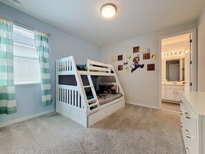 A child's bedroom with bunk beds, a window with curtains, a wall with Mario-themed decals, and a bathroom with a mirror and vanity. - Solara Resort Villa-9BR | Pool & Spa | Near Disney (Kissimmee)