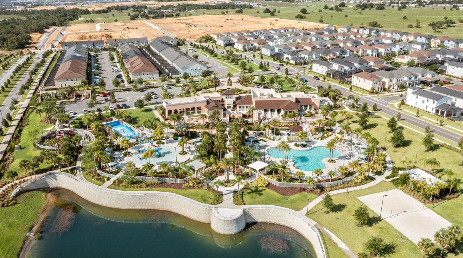 A residential area with a central swimming pool, multiple houses, and a large building with a curved roof.