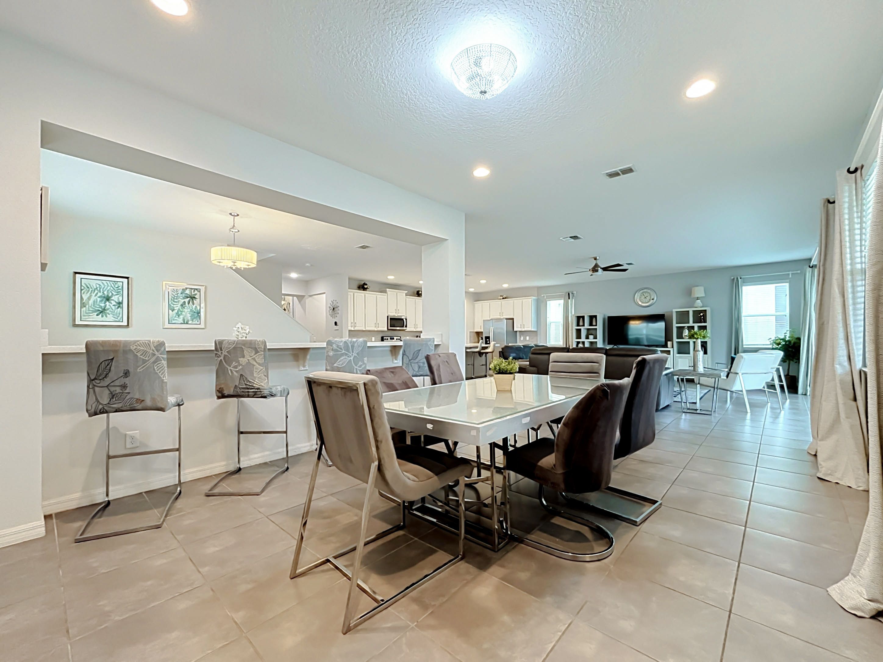 A spacious living area with a dining table, chairs, and a kitchen in the background.