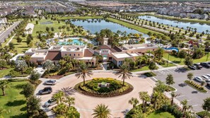 A large hotel with a central courtyard, multiple swimming pools, and a lake in the background. - Solara Resort Villa-9BR | Pool & Spa | Near Disney (Kissimmee)
