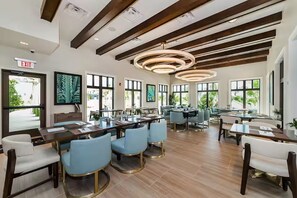 A modern restaurant with wooden beams, circular ceiling lights, and large windows. - Solara Resort Villa-9BR | Pool & Spa | Near Disney (Kissimmee)