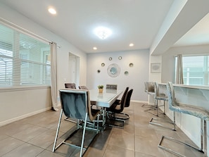 A modern dining area with a glass table, metal chairs, and a ceiling light. - Solara Resort Villa-9BR | Pool & Spa | Near Disney (Kissimmee)