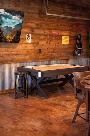 A billiards table in a room with wooden walls, a warning sign, and a laundry service sign. - Overwatch: HUGE Game Room, Hot Tub, FirePit, &More (Pigeon Forge)