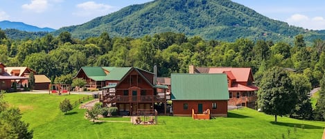 Eine Lodge mit mehreren Holzhütten, einer überdachten Terrasse und einer Bergkulisse.