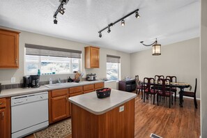 Una cocina moderna con armarios de madera, una isla central y un comedor con mesa y sillas.