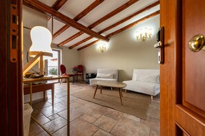 A room with a wooden ceiling, a white sofa, a small table, and a chair. - Vrbo Property (Catania)