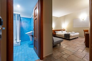 A hotel room with a shower, a bed, a bedside table, and a chair. - Vrbo Property (Catania)