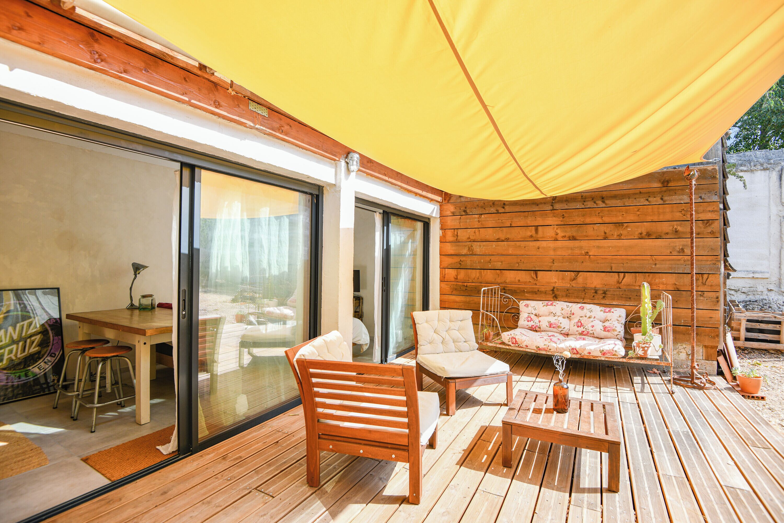 A wooden deck with a table, chairs, and a sofa.